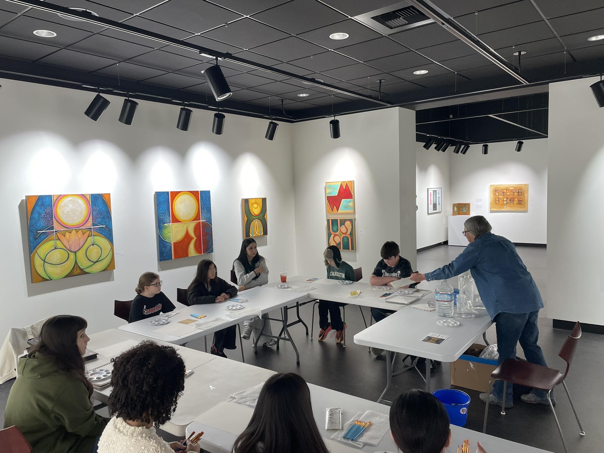 a small group of students doing water color at a gallery with an instructor.